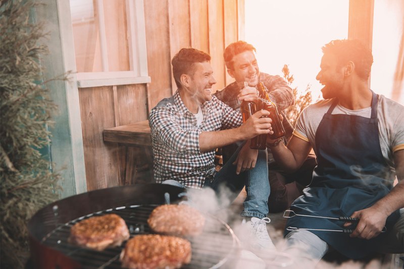 Friends enjoying beers by the barbecue.