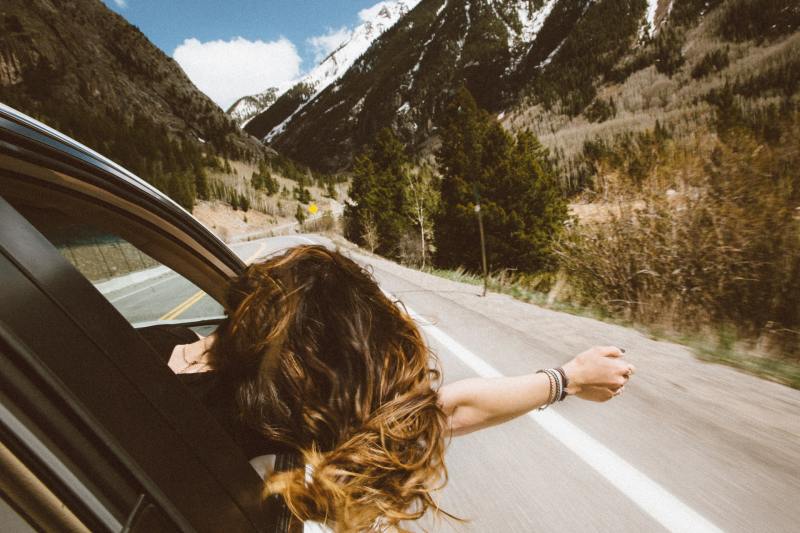 Woman leaning out of passenger window in a moving car.